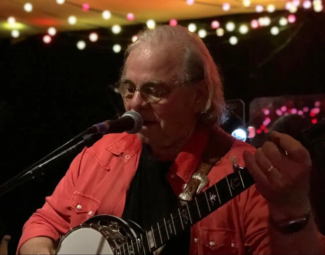 Dave Miller playing banjo under warm string lights